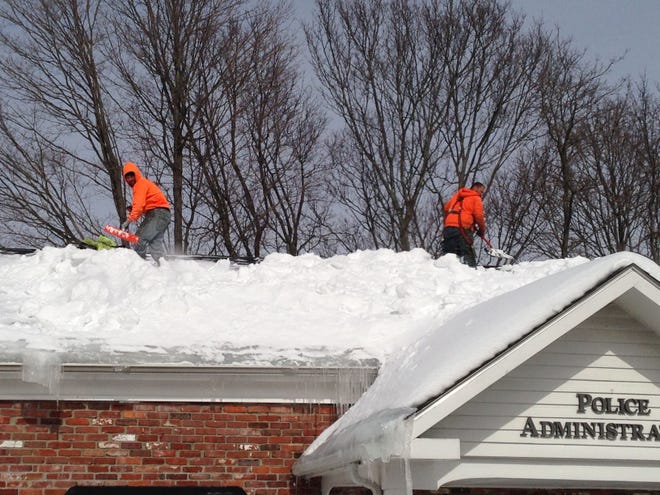 Nicholas Landry, left, and James Rawlinson clean snow from the roof of the police administration building Saturday in Bellingham. Daily News Staff Photo/Matt Tota