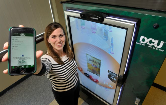 Gereen Langmeyer, manager of electronic services at Digital Credit Union, shows the DCU smartphone app as she stands next to a mobile payment vending machine at the DCU Operations Center in Marlboro. The vending machine uses a QR code so customers can pay for their snacks with a mobile phone.