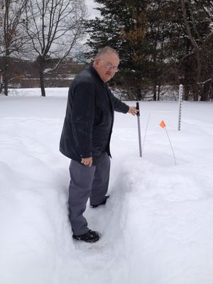 Meteorologist Alan Dunham demonstrates how to measure snow on a snow measuring board.