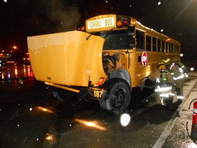 Newport firefighters look over one of the school buses involved in a suspicious incident Sunday night at Newport Elementary School, where two school buses were set on fire and a third tampered with.