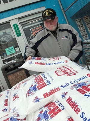 Jim Michonski grabs a bag of rock salt from a pallet outside Schwartz Hardware store on South Main Street Saturday afternoon prior to the blizzard hitting SouthCoast. MICHAEL SMITH/FALL RIVER SPIRIT