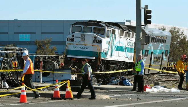 Workers walk near a Metrolink train that hit a truck and then derailed Tuesday, Feb. 24, 2015, in Oxnard, Calif. Three cars of the Metrolink train tumbled onto their sides, injuring dozens of people in the town 65 miles northwest of Los Angeles. (AP Photo/Mark J. Terrill)