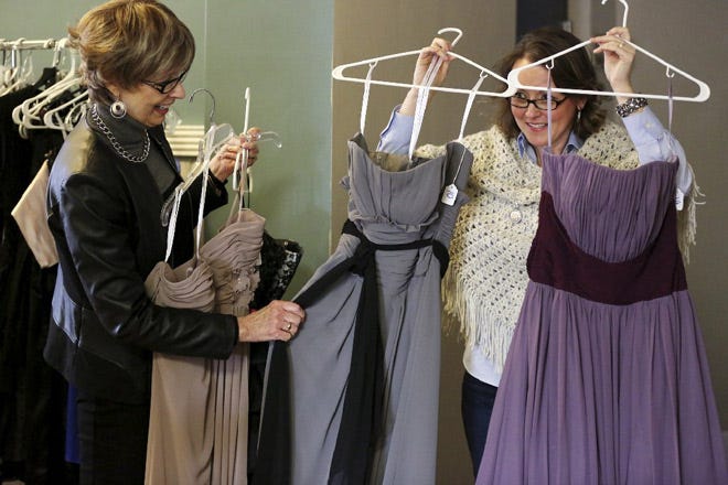 Volunteers Anita Robinson, left, and Christy Gianettino, show off a few of the 700 prom dresses Journey Fellowship Church in Galena is giving away.
