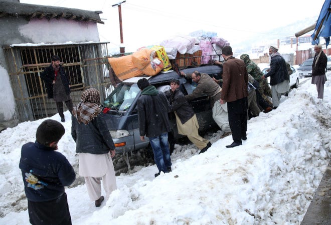 Afghan men try to free a car stuck in snow in Panjshir province northeast of the capital, Kabul. Their effort Wednesday followed a storm that led to avalanches in Panjshir and three other provinces.