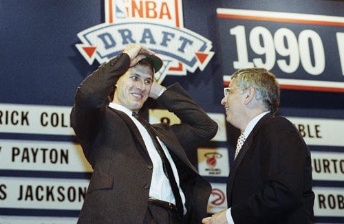 Alec Kessler of Georgia tries on his Houston cap while smiling at NBA Commissioner David Stern at the NBA draft in New York, June 27, 1990. Kessler was selected as the 12th draft pick by the Rockets.