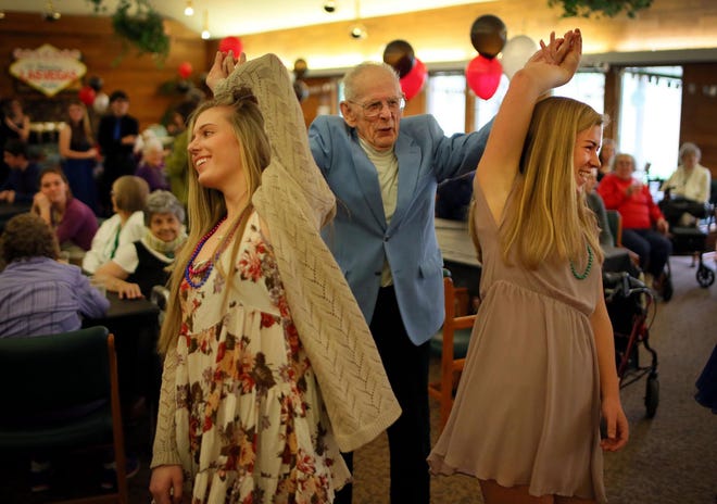 Bob Lyford, 92, spins his pair of dance partners, Churchill High School students Delaney Swan (left) and Lena Jensen, at Churchill Estates Retirement Community’s annual Senior Prom on Friday afternoon. (Brian Davies/The Register-Guard)