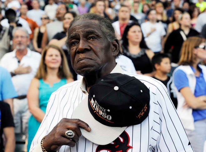 FILE - In a Aug. 24, 2013 file photo, former Negro Leaguer and Chicago White Sox player Minnie Minoso stands during the national anthem before a baseball game between the Chicago White Sox and the Texas Rangers, in Chicago. Major league baseball's first black player in Chicago, Minnie Minoso, has died. The Cook County medical examiner confirmed his death Sunday, March 1, 2015. There is some question about his age but the White Sox say he was 92. (AP Photo/David Banks, File)