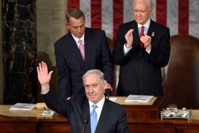 Israeli Prime Minister Benjamin Netanyahu waves as he speaks before a joint meeting of Congress on Capitol Hill in Washington, Tuesday, March 3, 2015. In a speech that stirred political intrigue in two countries, Netanyahu told Congress that negotiations underway between Iran and the U.S. would "all but guarantee" that Tehran will get nuclear weapons, a step that the world must avoid at all costs. House Speaker John Boehner of Ohio, left, and Sen. Orrin Hatch, R-Utah, are behind the prime minister.  (AP Photo/Susan Walsh)