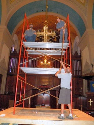 In preparation for Memorial Presbyterian Church's 125th anniversary celebration, workers polish 12 brass torchiers (pew lights) and seven double-cruciform chandeliers in an extensive effort to put a shine on the ceremony.
