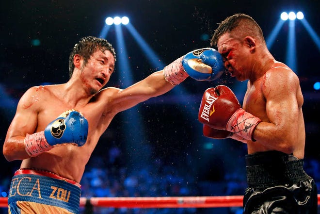 FILE - This July 19, 2014, file photo shows Chinese boxer Zou Shiming, left, delivering a punch to Colombian boxer Luis De La Rosa during the WBO international flyweight title match in Macau, China. China's double Olympic gold medalist goes after the IBF's 112-pound belt against Thailand's tough Amnat Ruenroeng in Macau this weekend, eager to justify his enormous popularity with a world title in just his seventh pro fight. (AP Photo/Dennis Ho, File)