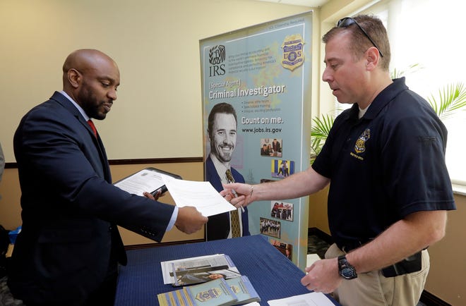 In this Feb. 6, 2015 photo, U.S. Marine Corps Veteran Arlington Robertson, of Fort Lauderdale, left, hands his resume to an Internal Revenue Service Special Agent, at the annual Veterans Career and Resource Fair in Miami. The Labor Department releases employment data for February on Friday, March 6, 2015. (AP Photo/Alan Diaz)