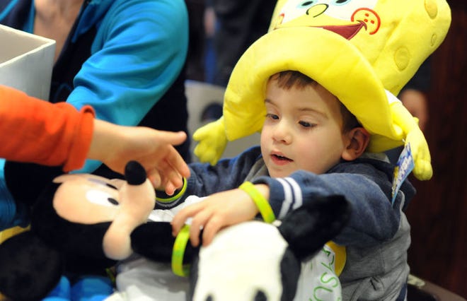 Ciarlo Liples, of Doylestown, gets a feel for his upcoming trip to Disney World as he plays with a Mickey Mouse doll during a surprise celebration Monday, March 9, 2015, in Lower Southampton. Ciarlo, who has spina bifida, received the trip from the Sunshine Foundation, which worked with Bucks Connect and teachers and students from Lower Moreland High School to raise funds.