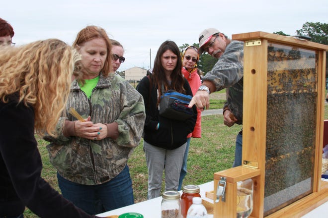 Marleena Griffith talks with Terri Hirt about honey while her sister, Leandra Griffith gets a beekeeping lesson from hive owner Larry Hirt at the recent Pine Ridge FFA Agriculture Expo.