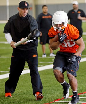 OSU running backs coach Marcus Arroyo tries to knock the ball away from Raymond Taylor (30) as part of a drill during Oklahoma State spring football practice at the Sherman E. Smith Training Center in Stillwater, Okla., Monday, March 9, 2015. Photo by Nate Billings, The Oklahoman