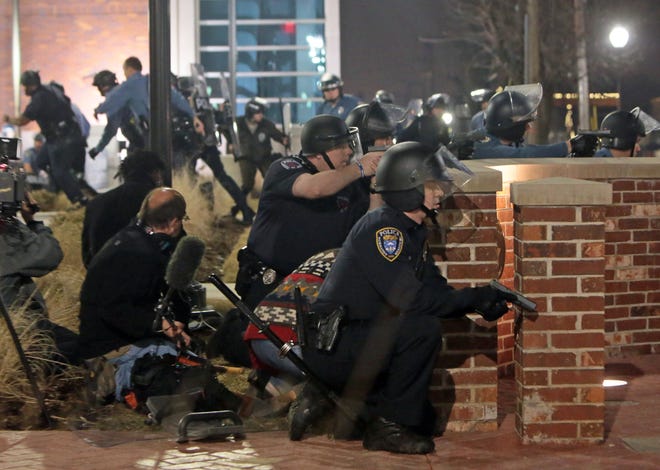 Police take cover after two officers were shot while standing guard in front of the Ferguson Police Station on Thursday, March 12.