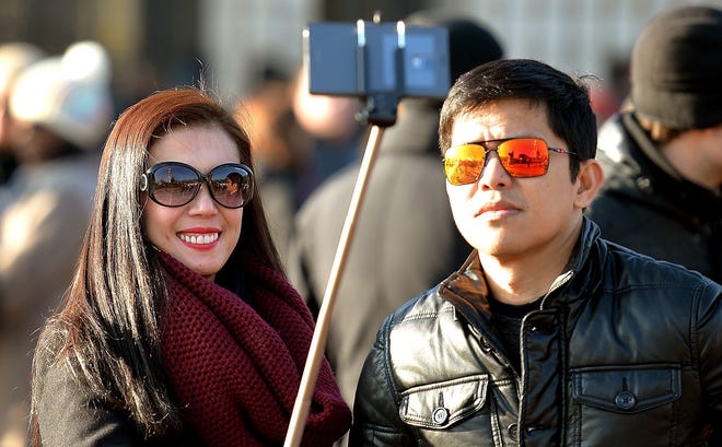 In this Jan. 23, 2015, file photo, tourists use a 'selfie stick' in London. A French palace and a British museum have joined the growing list of global tourist attractions that have banned "selfie sticks" _ devices visitors use to improve snapshots, but which critics say are obnoxious and potentially dangerous.