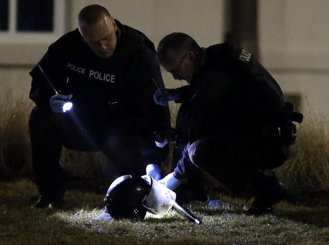 Police shine a light on a helmet as they investigate the scene where two police officers were shot outside the Ferguson Police Department Thursday.