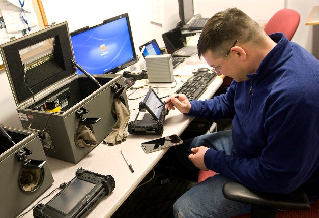 Mark Newth, a forensic science examiner in Connecticut, taps on an electronic device used to extract data from cell phones Feb. 13 in Meriden, Conn., at a state police forensic science laboratory.