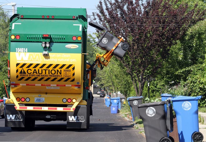 A Waste Management truck picks up a trash barrel in Edgewood on the first day of automated collection pickup.