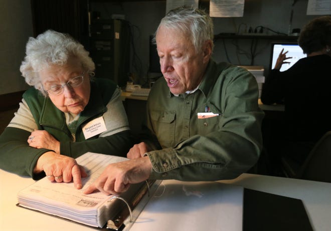 Church of Jesus Christ of Latter Day Saints Family History Center consultant Margaret Arthurs (left) helps Garry Compan leaf through ship passenger records on March 4, in Tallmadge. (Phil Masturzo/Akron Beacon Journal)