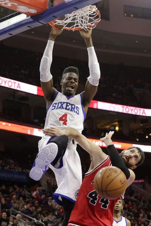 The 76ers' Nerlens Noel (4) hangs on the rim after dunking on the Bulls' Nikola Mirotic during a March 13 game.