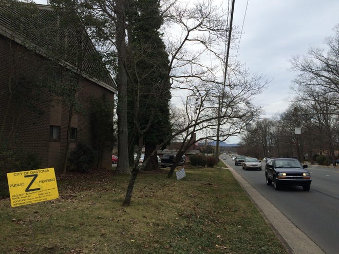 With Crowders Mountain visible in the distance, vehicles on Garrison Boulevard in Gastonia pass by Grier Apartments and approach the South New Hope Road intersection. A bright yellow sign informing residents about a March 5 zoning public hearing was still on the lawn Tuesday.