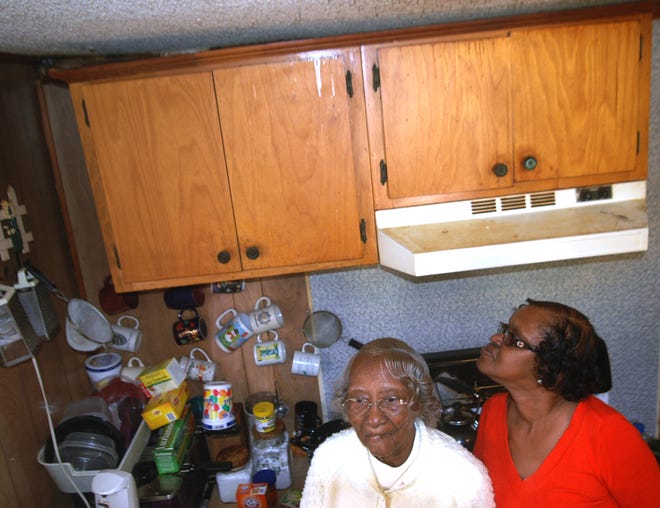 Pearl Styron, 98, left, and her niece Delores Wannamaker stand in the kitchen of their home near Oriental, where kitchen cabinets are separated from the wall and ceiling.