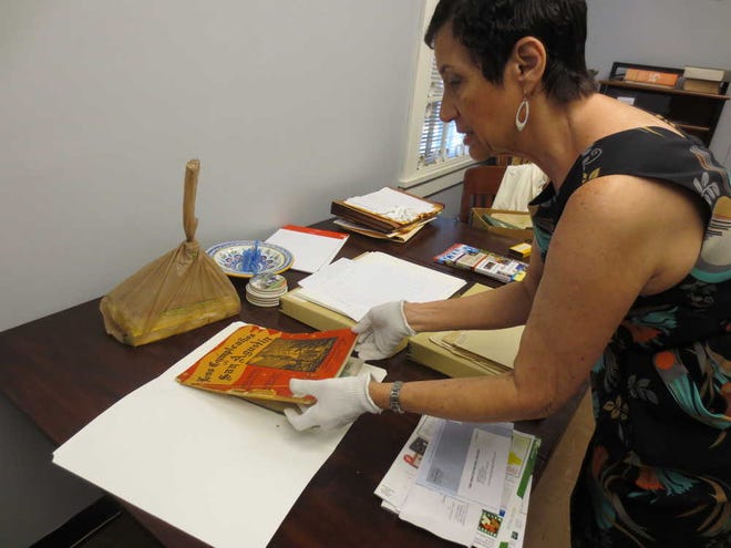 KIMEKO.MCCOY@STAUGUSTINE.COM St. Augustine Historical Society Executive Director Susan Parker skims through artifacts from St. Augustine's history including a booklet from the city's 375th anniversary.