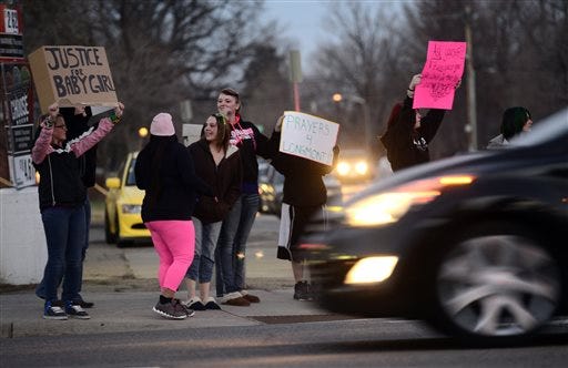 A group of protestors wave signs at passing cars while protesting against Dynel Lane on Thursday, March 19, 2015, in Longmont, Colo. Lane is accused of stabbing a pregnant woman in the stomach and removing her baby, while the expectant mother visited her home to buy baby clothes advertised on Craigslist authorities said. The baby did not survive. (AP Photo/The Daily Camera, Jeremy Papasso)