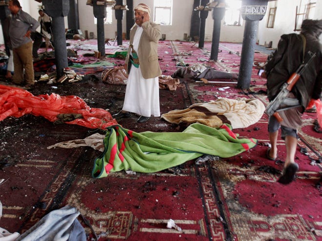 People stand amid bodies covered with blankets in a mosque after a suicide attack during the noon prayer in Sanaa, Yemen, on Friday.