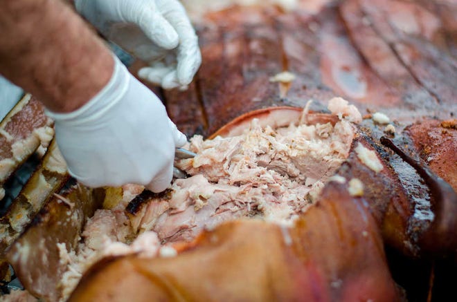 Noah Brendel pulls meat from the pig during an Athens Pig Roast presented by Athens Regional Health System at the West Broad Farmers Market in Athens, Ga., on Saturday, Mar. 21, 2015. The berkshire pig is from a local community meat co-op and was hormone free and pasture fead. (Taylor Craig Sutton/Staff, Taylorcraigsutton.com)