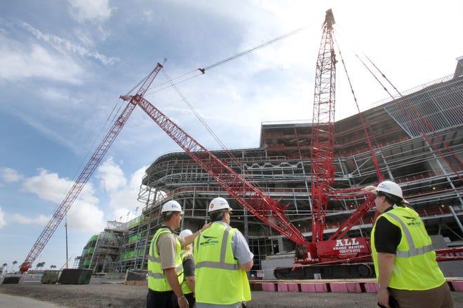 Len Moser, Barton Marlow, project director, left, and Andrew Booth, senior manager of public relations at the Speedway, right, show visitors the Manitowoc 2250 crawler crane Thursday at Daytona International Speedway. The crane — nicknamed “Big Red” — will be pulling down large sections of the old Sprint Tower for disassembly.
