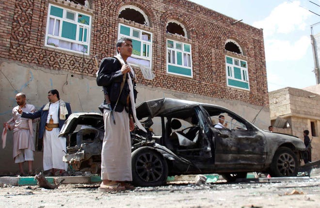 Houthi fighters stand near a damaged car after suicide attack in Sanaa, Yemen, Friday, March 20, 2015. Triple suicide bombers hit a pair of mosques crowded with worshippers in the Yemeni capital, Sanaa, on Friday, causing heavy casualties, according to witnesses. The attackers targeted mosques frequented by Shiite rebels, who have controlled the capital since September. (AP Photo/Hani Mohammed)