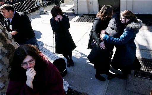 A woman is consoled as others cry as vehicles carrying the remains of the seven siblings killed in a house fire depart after funeral services, Sunday, March 22, 2015, in the Brooklyn borough of New York. The siblings, ages 5 to 16, died early Saturday when flames engulfed the Sassoon family home in the Midwood neighborhood of Brooklyn. Investigators believe a hot plate left on a kitchen counter set off the fire that trapped the children and badly injured their mother and another sibling. (AP Photo/Julio Cortez)