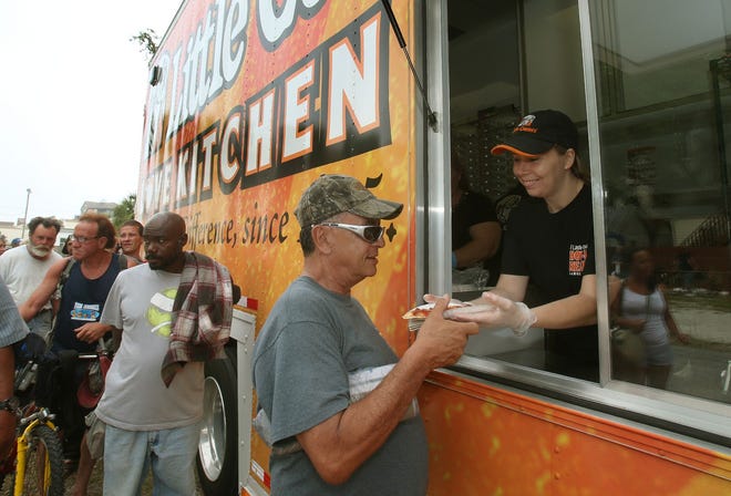 Amy Wray, a local Little Caesars Pizza employee, helps feed the homeless Friday from the national chain’s mobile Love Kitchen at Halifax Urban Ministries in Daytona Beach.