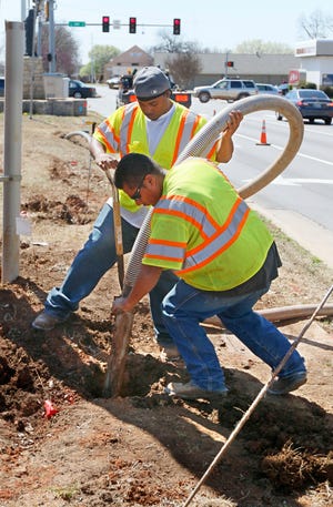 Frank Williams, left, and Jose Gonzales clear out a hole to find an underground pipe as they install fiber optic lines for an intelligent transportation system in March at Boulevard and Second Street. [PHOTO BY PAUL HELLSTERN, THE OKLAHOMAN]