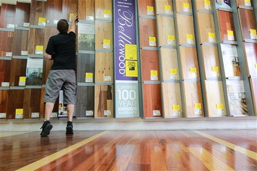 Kiel Skrobacz, an assistant store manager at Lumber Liquidators in Lutz, Fla., sticks yellow sale tags on products on Thursday, March 12, 2015. A "60 Minutes" expose reported the company's Chinese-made laminate flooring contained high levels of formaldehyde, a carcinogen. The founder and chairman of the company said Friday that the retailer currently has no plans to stop selling laminate flooring made in China, even as it continues to face fallout from the report that questioned the safety of such laminates. (AP Photo/Tampa Bay Times, Rachel Crosby)