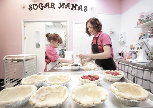 Jamie Anania, owner of Sugar Mamas Sweet Shop, gets assistance Wednesday from her daughter, Aelynn, 5, while cutting strips of dough for strawberry and blueberry pies at the downtown shop. Sugar Mamas opened in October and was approved for a $6,000 economic inducement grant. Anania said she is waiting on the money.