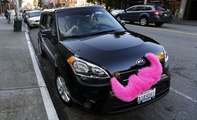 In this March 12, 2014, file photo, passenger Katie Baranyuk, left, and Dara Jenkins, right, a driver for the ride-sharing service Lyft, perform Lyft's trademark fist-bump as they pose for a photo in downtown Seattle.