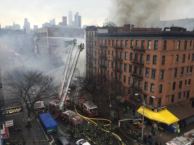 Smoke billows from a building in New York's East Village neighborhood at the scene of a large fire and a partial building collapse Thursday, March 26, 2015. Orange flames and black smoke billowed from the facade and roof of the building in Manhattan, near several New York University buildings and the Washington Square Park area. (AP Photo/John Minchillo)