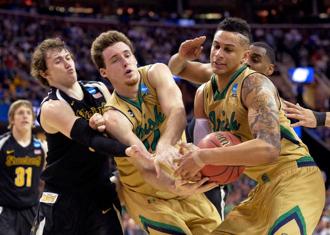 Notre Dame's Pat Connaughton, center, and Zach Auguste, right, wrestle the ball way from Wichita State's Evan Wessel during the second half of a college basketball game in the NCAA men's tournament regional semifinals, Thursday, March 26, 2015, in Cleveland. (AP Photo/David Richard)