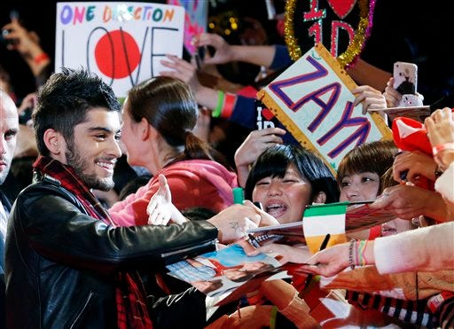 FILE - In this Sunday, Nov. 3, 2013 file photo, Zayn Malik of One Direction gives his autograph to Japanese fans during an event for their film "One Direction: This Is Us", in Makuhari near Tokyo.Chart-topping boy band One Direction says Zayn Malik has left the group. The band confirmed his departure Wednesday, March 25, 2015 in a statement. (AP Photo/Koji Sasahara, File)