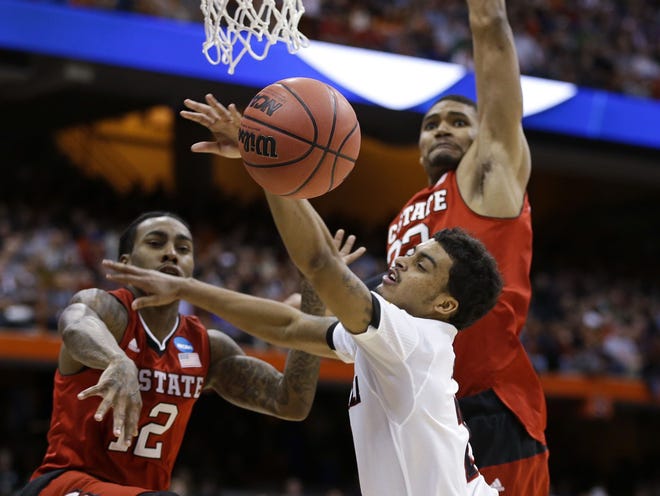 North Carolina State's Anthony Barber (12) fouls Louisville's Quentin Snider (2) during the first half of a regional semifinal in the NCAA men's college basketball tournament Friday in Syracuse, New York.