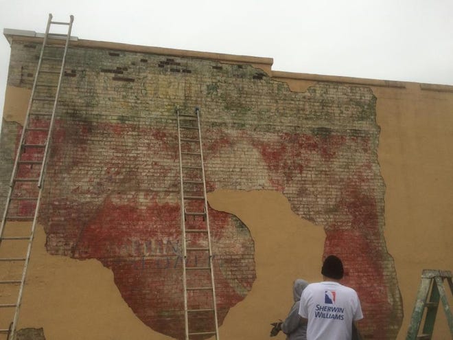 Two construction workers uncovered an old advertising mural underneath the outer wall of a building on Main Street in Mount Holly. The faded painting shows the distinctive Coca-Cola logo with ‘Rhyne’s Grocery’ scrolled across the building’s top edge.