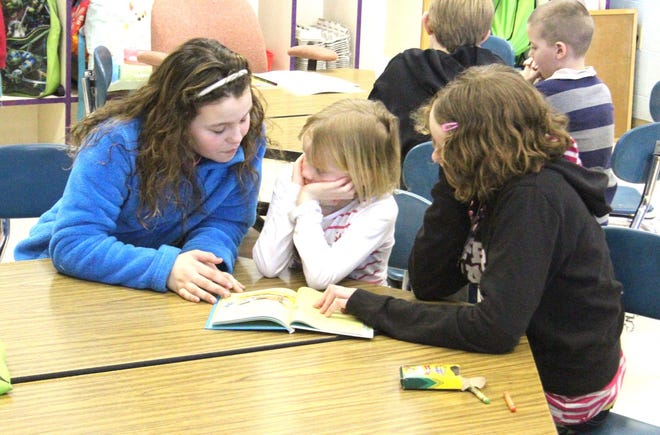 Pittsford fifth-graders Deveyn Toner (left) and Kiara Metzger (right) read to kindergartener Presley Hamilton on Older Day. JASON DAFNIS PHOTO