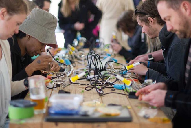 People works to solder circuitry together to make a Slingshot 'O' with LED lights during the TecTime maker playground, part of the Slingshot Festival, at Creature Comforts Brewing Company on Saturday, March 28, 2015, in Athens, Ga. (AJ Reynolds/Staff, @ajreynoldsphoto)