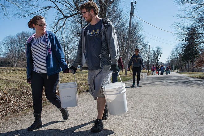 Cecelia Swanson and Jordan Truelson carry buckets of water back from Eureka Lake on Saturday afternoon on South Adams Road in Eureka. Participants walked nearly two and a half miles to raise awareness for people living in developing countries that may not have access to drinking water nearby.