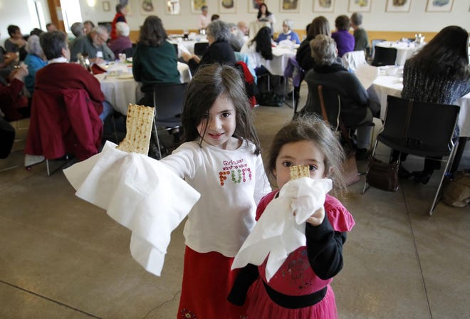 Six-year-old Aliyah Derfler (left) and her sister Ruti, 5, show off the matzoh they found hidden for them at the end of a interfaith Hunger Seder sponsored by the Jewish Federation of Lane County and the Jewish Community Relations Council held and held at Temple Beth. With a focus on children, the Passover Seder which seeks with its retelling of the Jewish people's liberation from slavery in Egypt typically ends with a search for hidden prizes by the youngsters at the gathering. (Chris Pietsch/The Register-Guard)