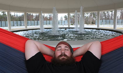Tate Reed, 36, relaxes in a hammock at the Onslow County Vietnam Veterans Memorial in the Lejeune Memorial Gardens in Jacksonville recently. Reed comes to there often to reflect and relax, finding the white noise of the fountain adding to the moment. The nylon hammock is supported by looped self-locking nylon straps which leave no marks behind. The name of Reed’s grandfather, Robert Lee Kraus, is one of the names inscribed on the monument.