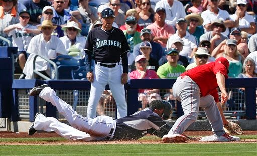 Seattle Mariners' Nelson Cruz dives safely back into third base with no view through his helmet as Los Angeles Angels third baseman David Freese tries to make a tag in the fourth inning of a spring training baseball game Monday, March 30, 2015, in Peoria, Ariz. (AP Photo/Lenny Ignelzi)
